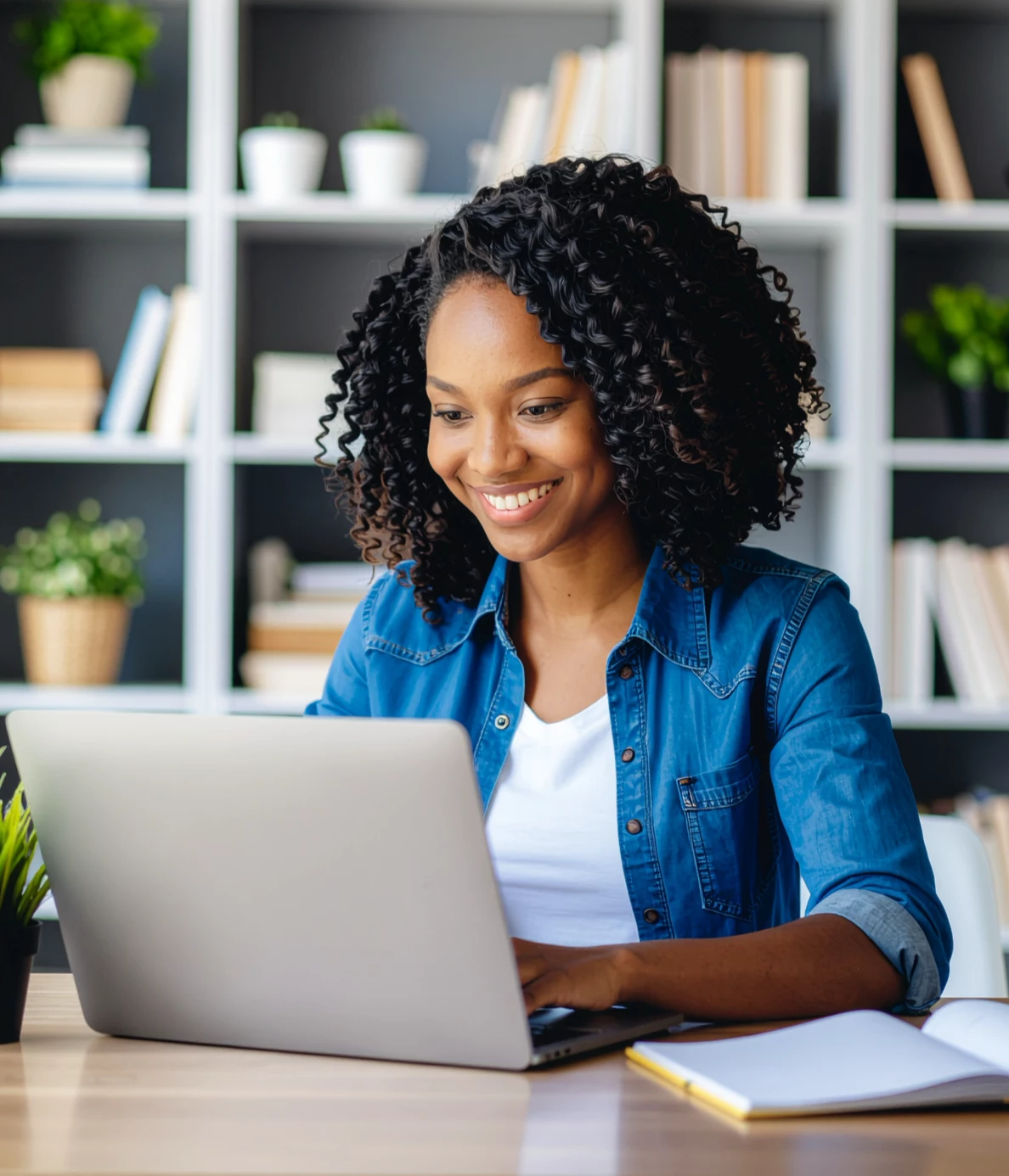 A woman sitting at a desk, working on a notebook computer